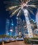 palm tree decorated with numerous lights at night on the Dubai Marina embankment with stunning skyscrapers in the background