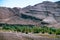 Palm tree oasis in desert terrain and mountains with tectonic foliage in the background. High Atlas. Morocco