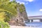 Palm tree on the sandy beach Naminoue topped by a huge rock with a Shinto Shrine at the top of a cliff and a highway passing in