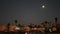 Palm trees and moon in twilight sky, California coast lifeguard, beach houses.