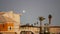 Palm trees and moon in twilight sky, California coast lifeguard, beach houses.