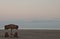 A palm umbrella stand above wooden adirondack chairs on a Pacific ocean beach