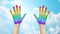 Palms of human hands painted in rainbow colors