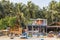 PALOLEM, GOA, INDIA - MARCH 18, 2019: View of colorful bungalows with tourists and fishing boats with locals on the sandy shore of