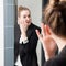 Pampering beautiful young smart woman applying eye concealer in mirror