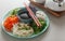 Pan Asian trendy Homemade vegetarian Poke Bowl with Rice, fresh vegetables, edible seaweeds and soy sauce, served with chopsticks