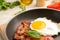 Pan with fried sunny side up egg and bacon on table