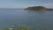 Pan left from a small island islet towards holidays resorts on an island and ends with vacation small boats in the foreground.