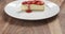 pan reveal of strawberry cheesecake on plate on wood table