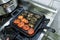 Pan and a square pan with dolma and tomatoes on a gas oven in the kitchen of the restaurant