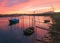 Panaromic shot of a beautiful colorful sunset on the seashore with fishing boats