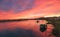 Panaromic shot of a stunning vibrant sunrise over a lakeside with empty fishing boats