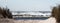 Panaromic view looking through the sand dunes of large ocean waves crashing on the beach