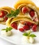 Pancake filled with strawsberries and garnished with mint, syrop and whipped cream