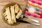 Pancake rolls in plate, piece of pancake on fork, mayonnaise in bowl on napkin, knife on wooden table. Top view