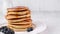 Pancake stack with blueberries and maple syrup on white plate, copy space.