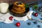 Pancakes with berries blueberries and cherries.pancakes in a frying pan on a blue table with a plate of fresh juicy berries on a