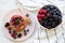 Pancakes with berries and honey on a pink plate, bowl of berries, top view.