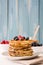 Pancakes with blueberries, raspberry and honey on blue wood