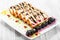 Pancakes with cream cheese, prunes, cherries decorated with chocolate and gold