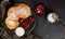 Pancakes with fruit jam, cherries, sour cream and icing sugar on black slate over dark background