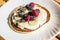 Pancakes with raspberries, blueberries, bananas and honey. Healthy summer breakfast, homemade classic american pancakes.