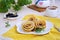 Pancakes, rolled up in the shape of a rose flower, on a white plate on a light concrete background