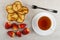 Pancakes in saucer, strawberries, fork, cup of tea on saucer on table. Top view