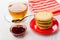 Pancakes on saucer, tea, spoon, red napkin, bowl with jam