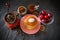 Pancakes with sour cream, coffee in glass cup, coffee beans in vintage crusher, plums in transparent bowl, dried lemon