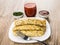 Pancakes with stuffing in white plate, fork, tomato juice, dill