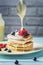 Pancakes are watered with condensed milk. Tasty breakfast with berries. Dessert with currants and blueberries close-up