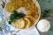 Pancakes with zucchini and sweet corn, served with sour cream, parsley and dill. Vegetarian food.