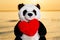 Panda Bear stuffed plush toy with Red Fluffy Heart at the sunrise in front of the lake. Love, Romance and Friendship