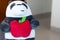 Panda plush toy holding a red apple with a happy face