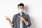 Pandemic lifestyle, healthcare and medicine concept. Young guy in face mask inviting look here, pointing fingers left at