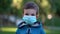 Pandemic, portrait of little boy with medical face mask standing outdoor.