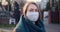 Pandemic situation. Portrait of young blonde woman wearing face protection mask outdoors during COVID-19 virus lockdown.