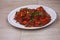 Paneer Chilis is an Indian dish, paneer cubes with tomatoes, onions, spring onions, chilli sauce. served on rustic wooden