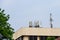 Panel antennas of a mobility cell site on the roof of a concrete building against a blue sky