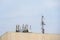 Panel antennas of a mobility cell site on the roof of a concrete building against a blue sky