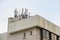 Panel antennas of a mobility cell site on the roof of a concrete building against a blue sky