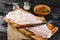 Pangasius fillet on a wooden cutting board with spices and knife on a black wooden background