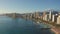 Panning aerial drone slowly flying over a colorful Honolulu Skyline while Sunset in Oahu, Hawaii with Waikiki Beach