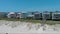 panning aerial footage of the beachfront homes along the sandy beach with pelicans flying in the air and a man flying a kite