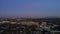 panning aerial footage of office buildings, homes and hotels in the city skyline with lights at sunset with cars and trucks