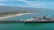 panning aerial footage of Stearns Wharf Pier with blue ocean water, boats and yachts sailing and people walking and cars driving