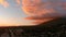 Panning aerial footage of a stunning sunset with powerful clouds and cars driving on the street surrounded by buildings