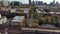 panning aerial footage of train riding on the tracks with autumn trees, cars on the street and skyscrapers, hotels