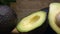 Panning camera reveals freshly cut avocado on a wooden chopping board
